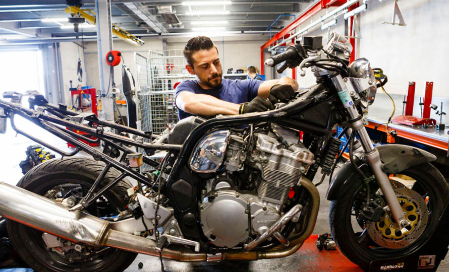 Un homme répare une moto accidentée dans un garage