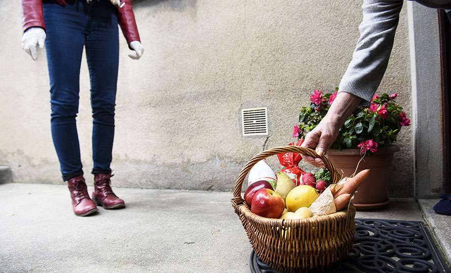Femme qui pose un panier de légumes devant une porte
