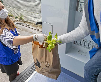 Un homme du Secours Populaire donne un sac de légumes à une femme