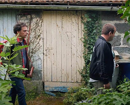 Deux hommes devant un logement dans un jardin