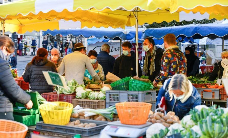 Des personnes réunies autour d'un étal de fruits et légumes sur un marché