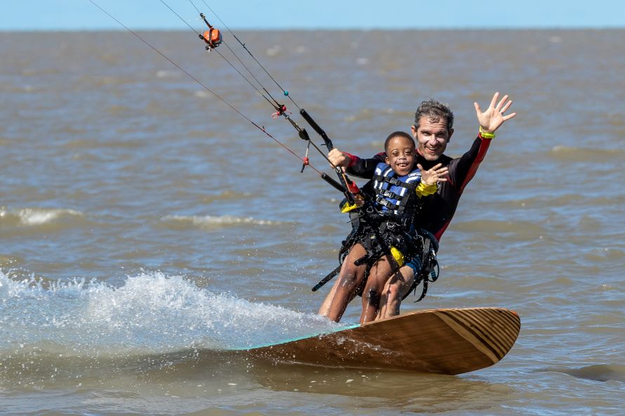 Yann Dejou promène un enfant handicapé sur sa planche de kitesurf.