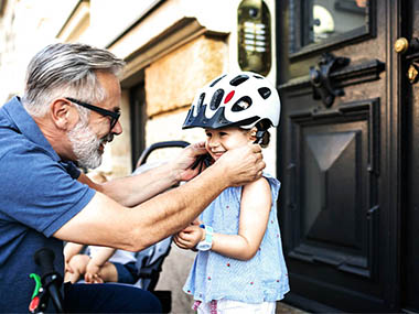 Un homme attache un casque à vélo sur la tête d’une petite fille